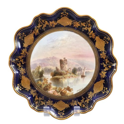 fig 4. A set of four late nineteenth-century Aynsley porcelain cabinet plates featuring hand-painted landscape scenes surrounded by cobalt blue rims with heavy gold foliage gilding.