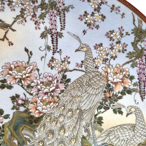 fig 2. A large circular Japanese Satsuma ceramic charger featuring raised enamel illustrations of peacocks, wisteria, and peonies on a cream crackle glaze background.