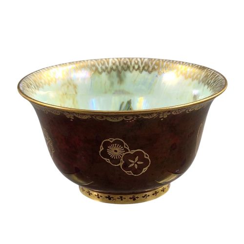 fig 2. A deep red ceramic bowl with a flared rim, featuring gilded motifs on the exterior and an iridescent opalescent glazed interior.