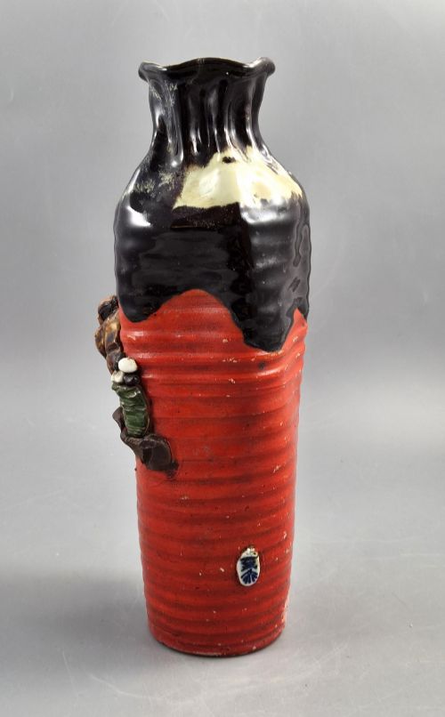 fig 2. A tall Japanese Sumida Gawa ceramic vase featuring a ribbed red base, applied relief figures of sages on a cliff, and a heavy dark drip glaze around the rim.