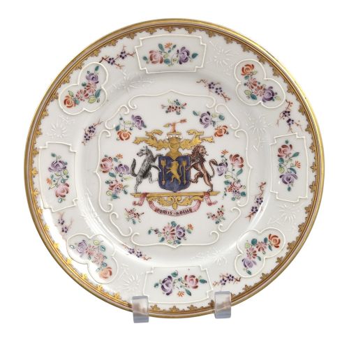 fig 1. A pair of circular white porcelain plates featuring a central coat of arms, hand-painted floral sprays, raised enamel details, and gilded rims.
