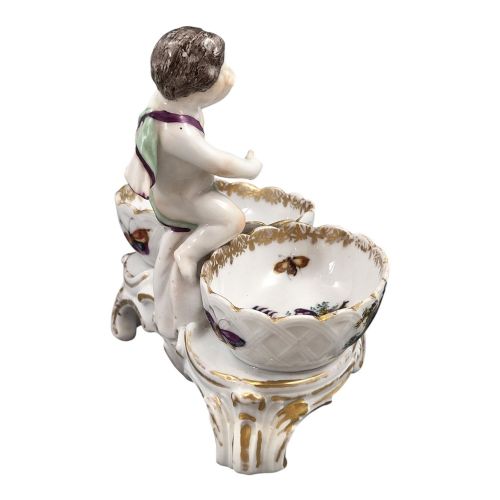 fig 4. A 19th-century German hard-paste porcelain double salt cellar featuring a central sculpted figure of a cherub flanked by two shell-shaped bowls hand-painted with birds and insects.