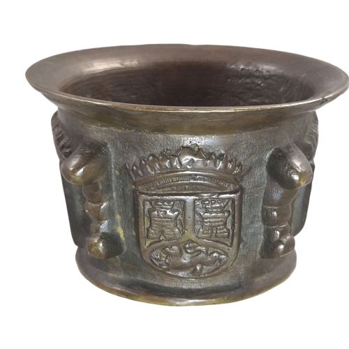 fig 1. A heavy 17th-century cast bronze apothecary mortar featuring raised heraldic coat of arms motifs and side lugs around a flared rim.