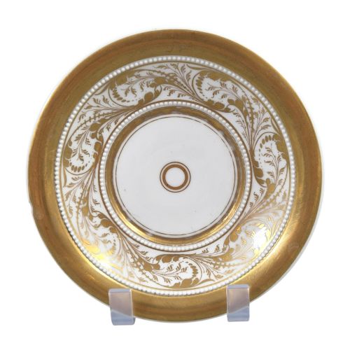 fig 1. An antique white and gilt porcelain presentation cup with an elevated loop handle sitting on a matching gilded saucer.
