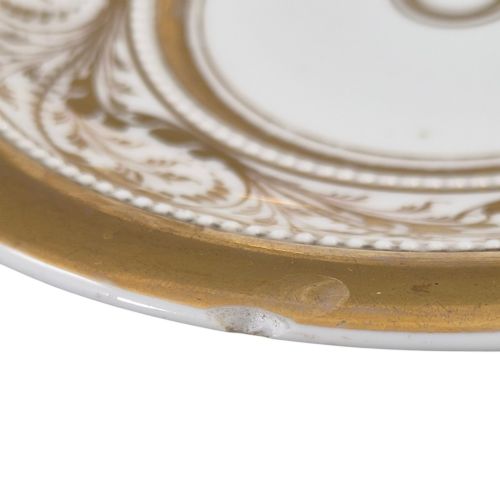 fig 2. An antique white and gilt porcelain presentation cup with an elevated loop handle sitting on a matching gilded saucer.