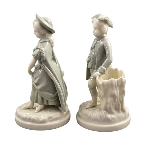 fig 1. A pair of late Victorian grey and cream glazed porcelain figural salts depicting a man and woman beside hollow tree stump vessels.