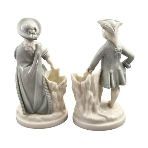 fig 2. A pair of late Victorian grey and cream glazed porcelain figural salts depicting a man and woman beside hollow tree stump vessels.