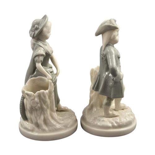 fig 3. A pair of late Victorian grey and cream glazed porcelain figural salts depicting a man and woman beside hollow tree stump vessels.