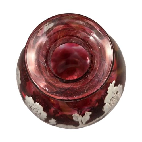 fig 2. A three-piece ruby red glass vanity set featuring floral sterling silver overlay details across two stoppered bottles and a cylindrical beaker.