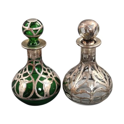fig 1. A pair of Art Nouveau perfume bottles featuring detailed sterling silver overlay in intricate floral lattice patterns on green and clear glass bases with matching glass stoppers.