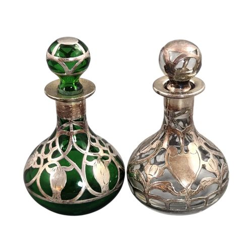 fig 3. A pair of Art Nouveau perfume bottles featuring detailed sterling silver overlay in intricate floral lattice patterns on green and clear glass bases with matching glass stoppers.