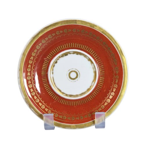 fig 2. A red and gilded French Empire porcelain cabinet cup and matching saucer featuring a raised white lion mask handle detail.
