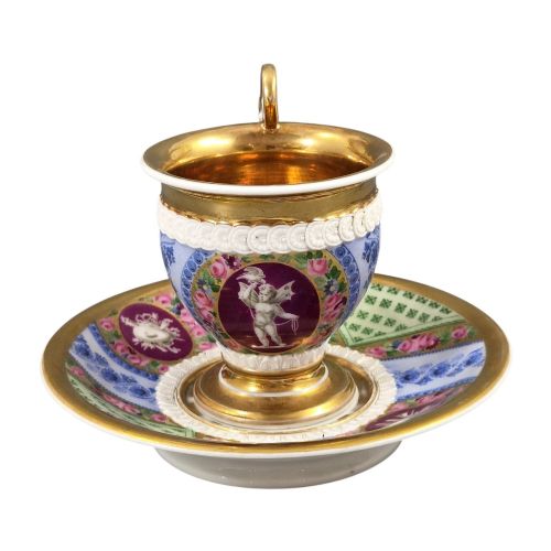 fig 3. A nineteenth-century French Vieux Paris porcelain cabinet cup and matching saucer featuring gold gilding, multi-coloured hand-painted panels, and a high-loop lion mask handle.