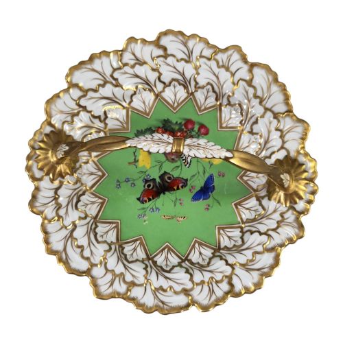 fig 5. A Regency Flight, Barr and Barr Worcester porcelain handle basket featuring a bright green central reserve decorated with hand-painted butterflies and berries, surrounded by a leaf-moulded rim and gilt handle.