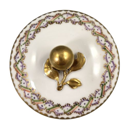 fig 3. A white Sevres porcelain teapot featuring polychrome geometric enamel borders, gilt trim, a rounded body, and a gilded spherical lid finial.