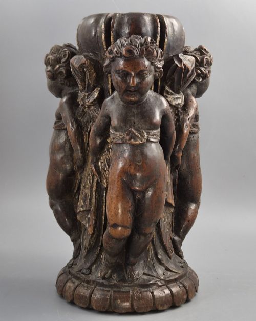 fig 2. A dark carved walnut Italian Baroque torchiere base featuring three sculpted putti figures standing around a central fluted shaft on a gadrooned circular base.