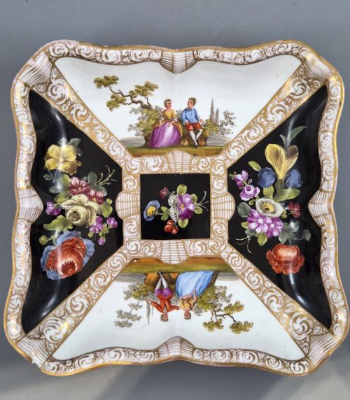 fig 3. A square shaped Meissen porcelain dish decorated with hand-painted Watteau scenes, floral reserves on a black ground, and gilded scroll borders.
