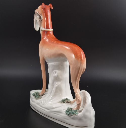 fig 2. A pair of antique Victorian Staffordshire earthenware figures depicting standing orange greyhounds holding grey hares in their jaws on white bases.