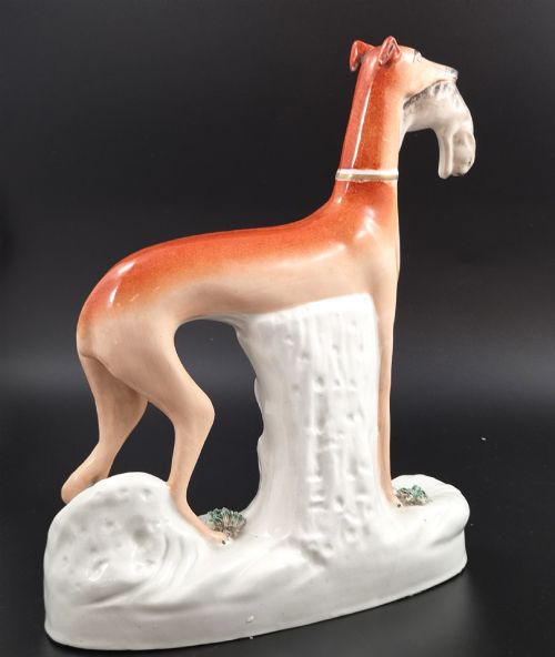 fig 3. A pair of antique Victorian Staffordshire earthenware figures depicting standing orange greyhounds holding grey hares in their jaws on white bases.