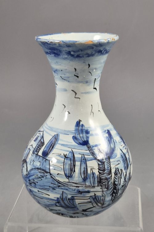 fig 1. An antique bulbous blue and white maiolica ceramic vase decorated with a hand-painted architectural landscape scene and a flared rim.