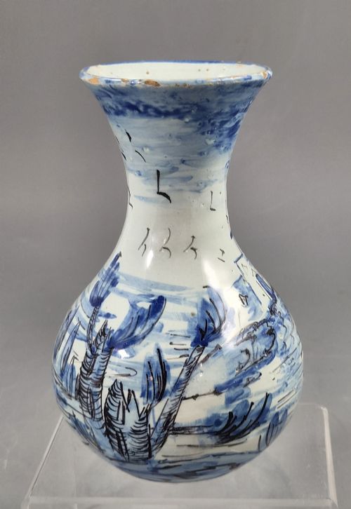 fig 2. An antique bulbous blue and white maiolica ceramic vase decorated with a hand-painted architectural landscape scene and a flared rim.