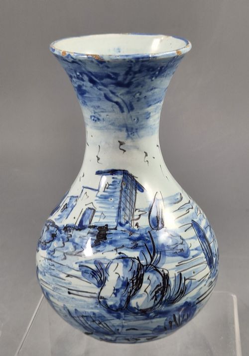 fig 4. An antique bulbous blue and white maiolica ceramic vase decorated with a hand-painted architectural landscape scene and a flared rim.