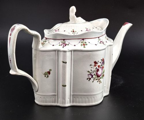 fig 2. An off-white earthenware commode-shaped teapot decorated with hand-painted floral sprays, red borders, and a seated widow finial on the lid.