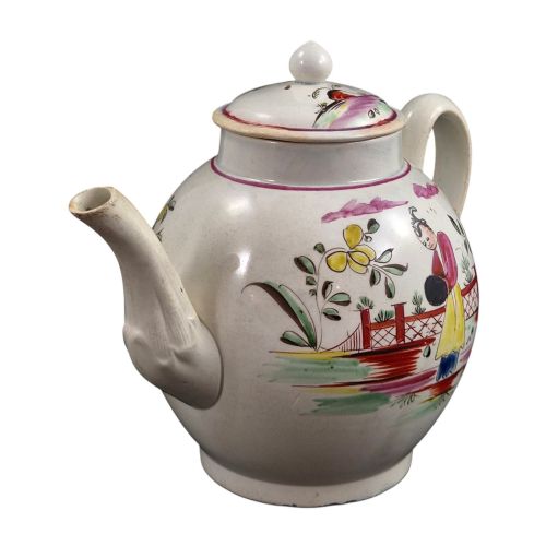 fig 5. An 18th-century creamware teapot featuring hand-painted polychrome Chinoiserie figures on a cream glaze background with a curved spout and loop handle.