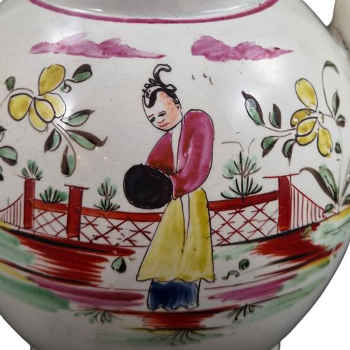fig 6. An 18th-century creamware teapot featuring hand-painted polychrome Chinoiserie figures on a cream glaze background with a curved spout and loop handle.