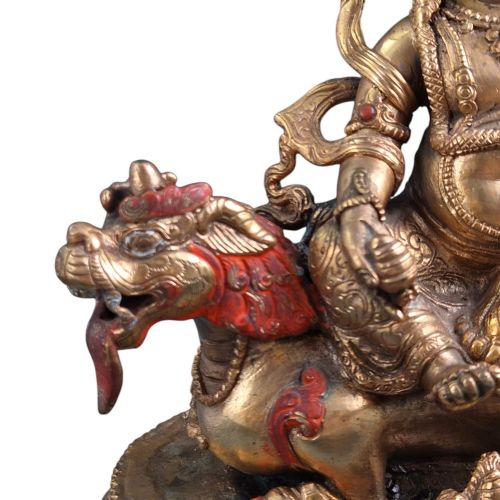 fig 2. A gilt bronze figure of the deity Jambhala crowned and adorned with jewellery, seated upon a snow lion atop an oval lotus pedestal base with red and blue painted accents.
