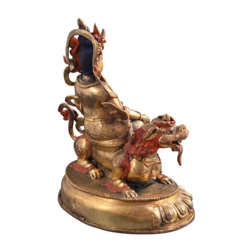fig 6. A gilt bronze figure of the deity Jambhala crowned and adorned with jewellery, seated upon a snow lion atop an oval lotus pedestal base with red and blue painted accents.