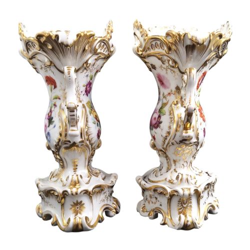 fig 1. A pair of ornate white and gilded porcelain Rococo vases featuring hand-painted floral bouquets, pierced rims, and scroll handles.