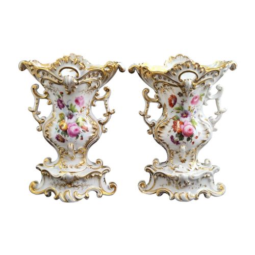 fig 2. A pair of ornate white and gilded porcelain Rococo vases featuring hand-painted floral bouquets, pierced rims, and scroll handles.