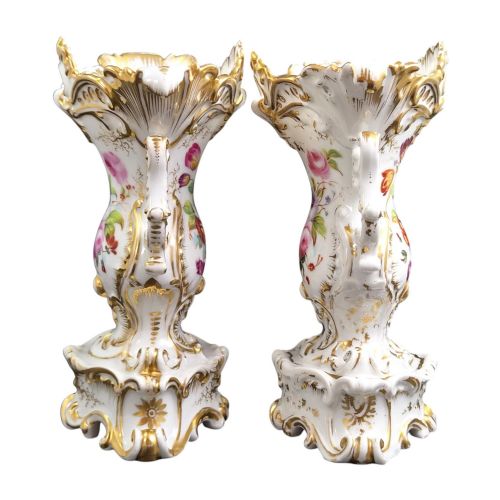 fig 3. A pair of ornate white and gilded porcelain Rococo vases featuring hand-painted floral bouquets, pierced rims, and scroll handles.