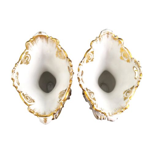 fig 4. A pair of ornate white and gilded porcelain Rococo vases featuring hand-painted floral bouquets, pierced rims, and scroll handles.