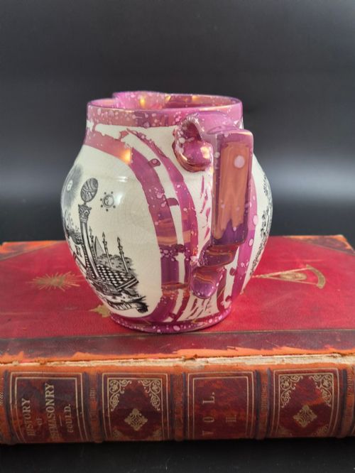 fig 1. An English earthenware jug featuring pink splash lustre glaze trim and a central black transfer-printed Masonic emblem.