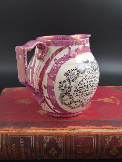 fig 2. An English earthenware jug featuring pink splash lustre glaze trim and a central black transfer-printed Masonic emblem.