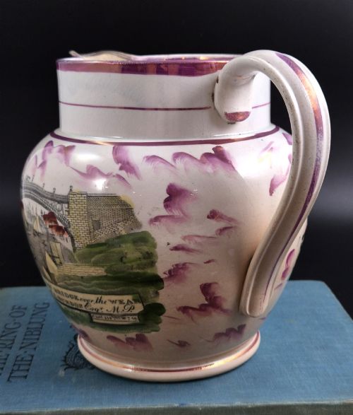 fig 1. An antique cream earthenware jug decorated with pink splash lustre glaze and a central transfer print depicting the Iron Bridge over the Wear.
