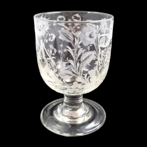 fig 2. A clear lead-glass rummer featuring detailed wheel-engraved fraternal symbols, including a central cross, all-seeing eye, crowns, and floral garlands, resting on a short stem and circular foot.