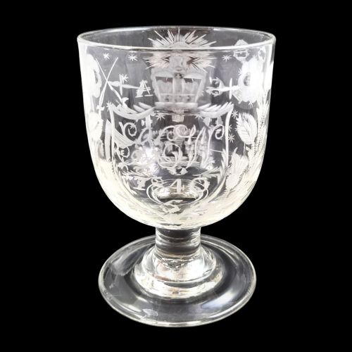 fig 4. A clear lead-glass rummer featuring detailed wheel-engraved fraternal symbols, including a central cross, all-seeing eye, crowns, and floral garlands, resting on a short stem and circular foot.