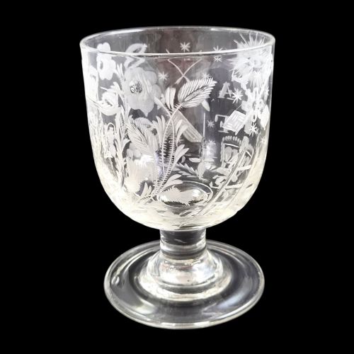 fig 5. A clear lead-glass rummer featuring detailed wheel-engraved fraternal symbols, including a central cross, all-seeing eye, crowns, and floral garlands, resting on a short stem and circular foot.
