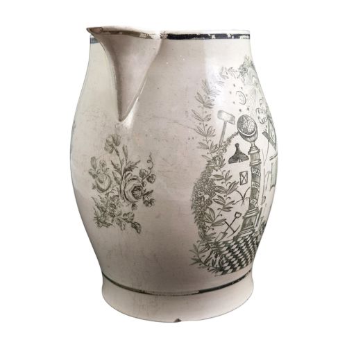 fig 3. A Georgian Staffordshire creamware jug featuring transfer-printed olive-green Masonic iconography framed by a leafy scrollwork wreath.