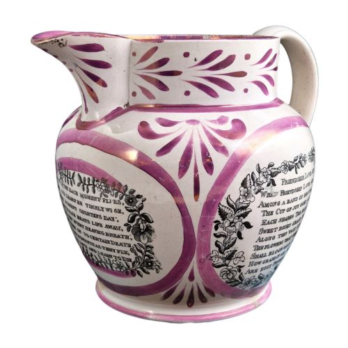 fig 3. An antique white earthenware jug decorated with pink metallic lustre foliage borders and a black transfer-printed Masonic emblem featuring twin columns and symbolic motifs.
