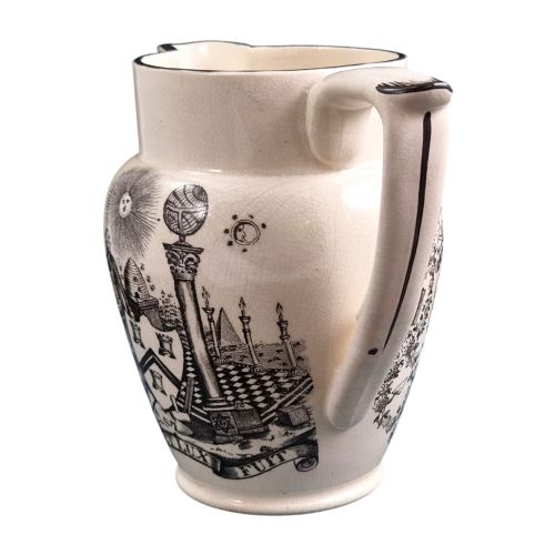 fig 1. A creamware ceramic jug featuring detailed black transfer prints of Masonic emblems, including classical columns, a beehive, and a coat of arms.