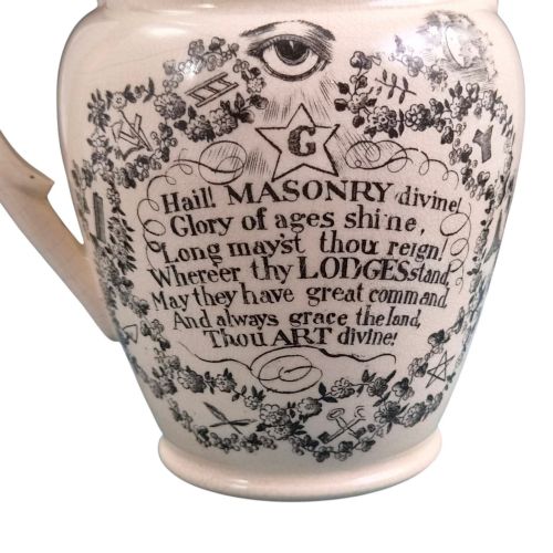 fig 3. A creamware ceramic jug featuring detailed black transfer prints of Masonic emblems, including classical columns, a beehive, and a coat of arms.