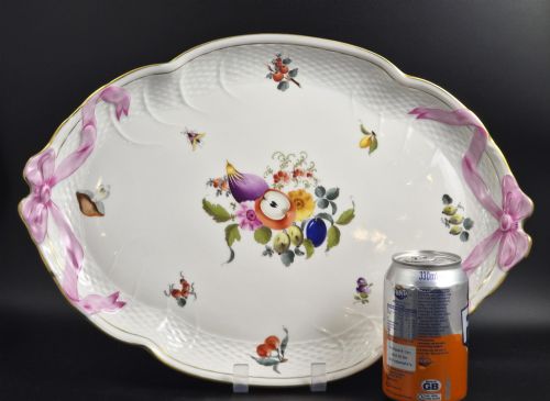 fig 1. An oval white porcelain tray featuring hand-painted fruit and insect motifs, moulded basketweave border, pink painted ribbon handles, and a gilded rim.