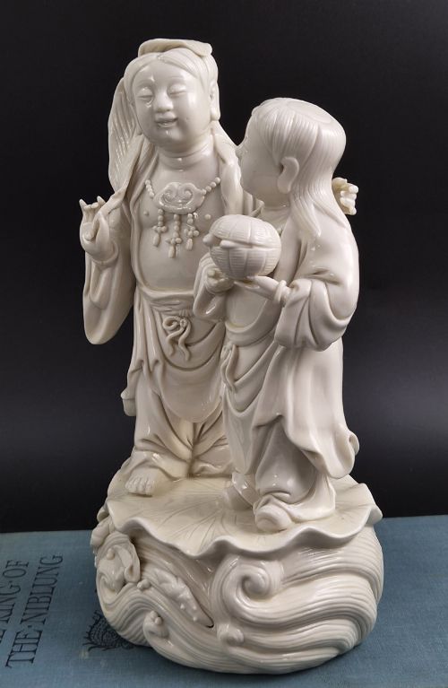 fig 3. A Qing Dynasty Blanc-de-Chine white porcelain figure group depicting the Hehe Erxian standing on a stylised lotus and wave base.