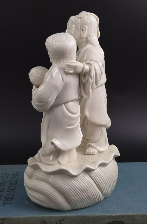fig 4. A Qing Dynasty Blanc-de-Chine white porcelain figure group depicting the Hehe Erxian standing on a stylised lotus and wave base.