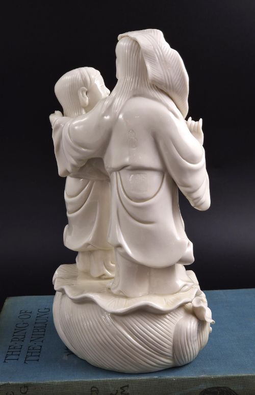 fig 6. A Qing Dynasty Blanc-de-Chine white porcelain figure group depicting the Hehe Erxian standing on a stylised lotus and wave base.