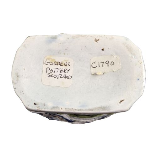 fig 4. An 18th-century Prattware earthenware tea canister featuring relief-moulded depictions of two Georgian Macaroni figures in blue, ochre, and green underglaze glazes against an off-white background.